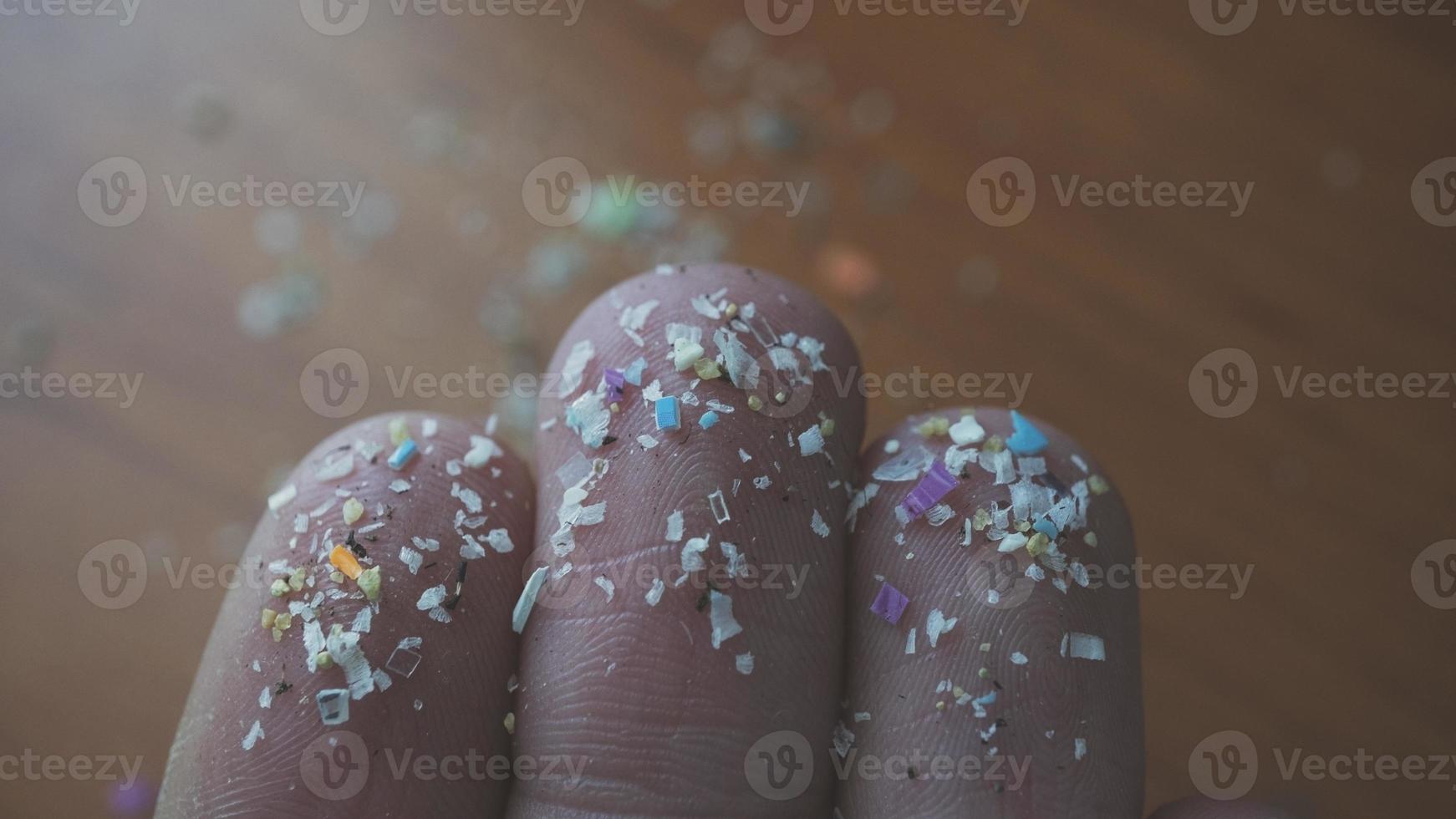 toma lateral de primer plano de microplásticos en los dedos humanos. concepto de contaminación del agua y calentamiento global. idea del cambio climático. enfoque suave en un montón de microplástico que no se puede reciclar. foto