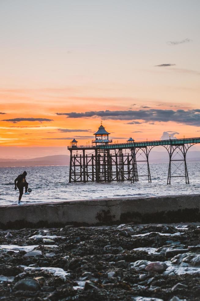 Man playing football in the beach at sunset time. photo