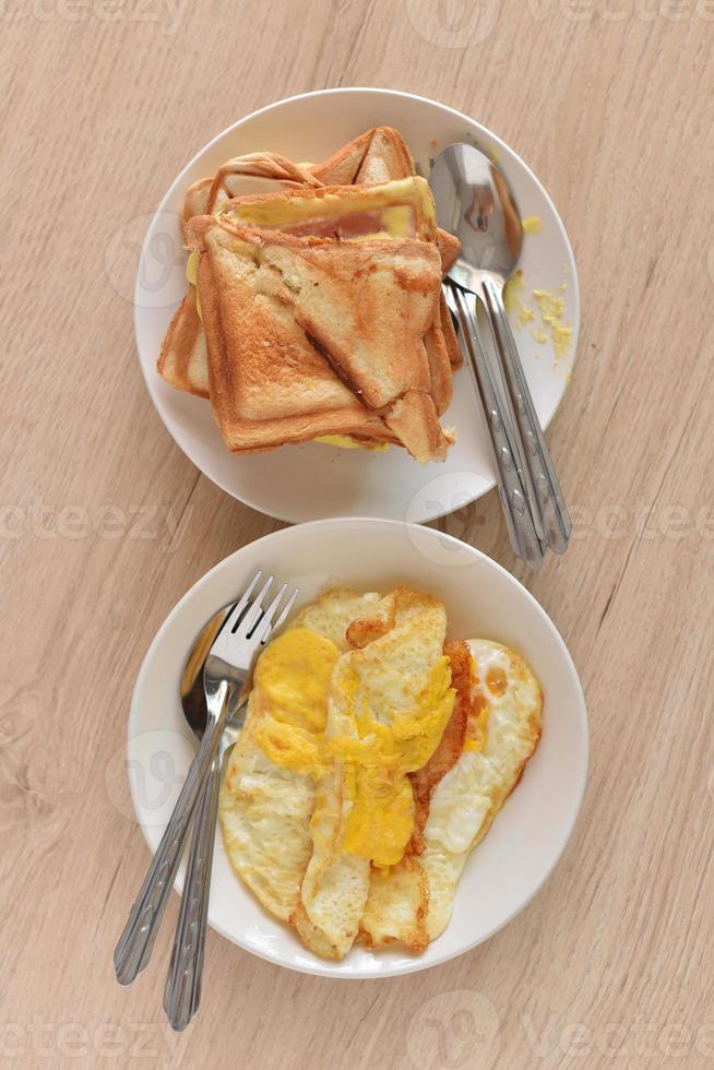 pan tostado huevos fritos en un plato blanco sobre una mesa de madera. foto