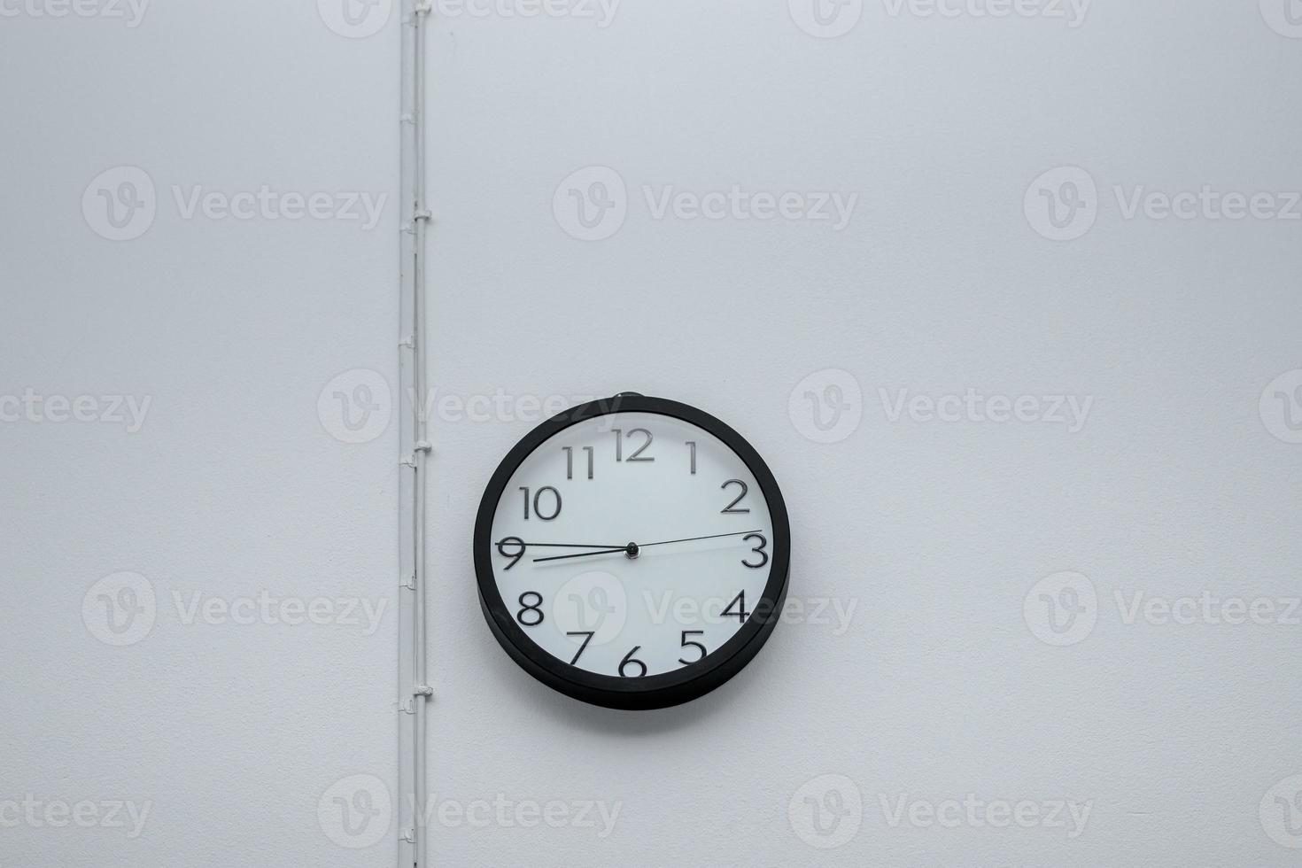 Black wall clock with white cement photo