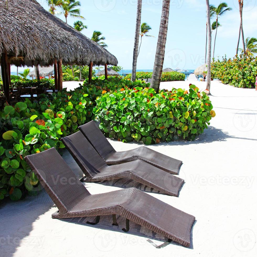 Relax on tropical beach in the sun on deck chairs under umbrella. photo
