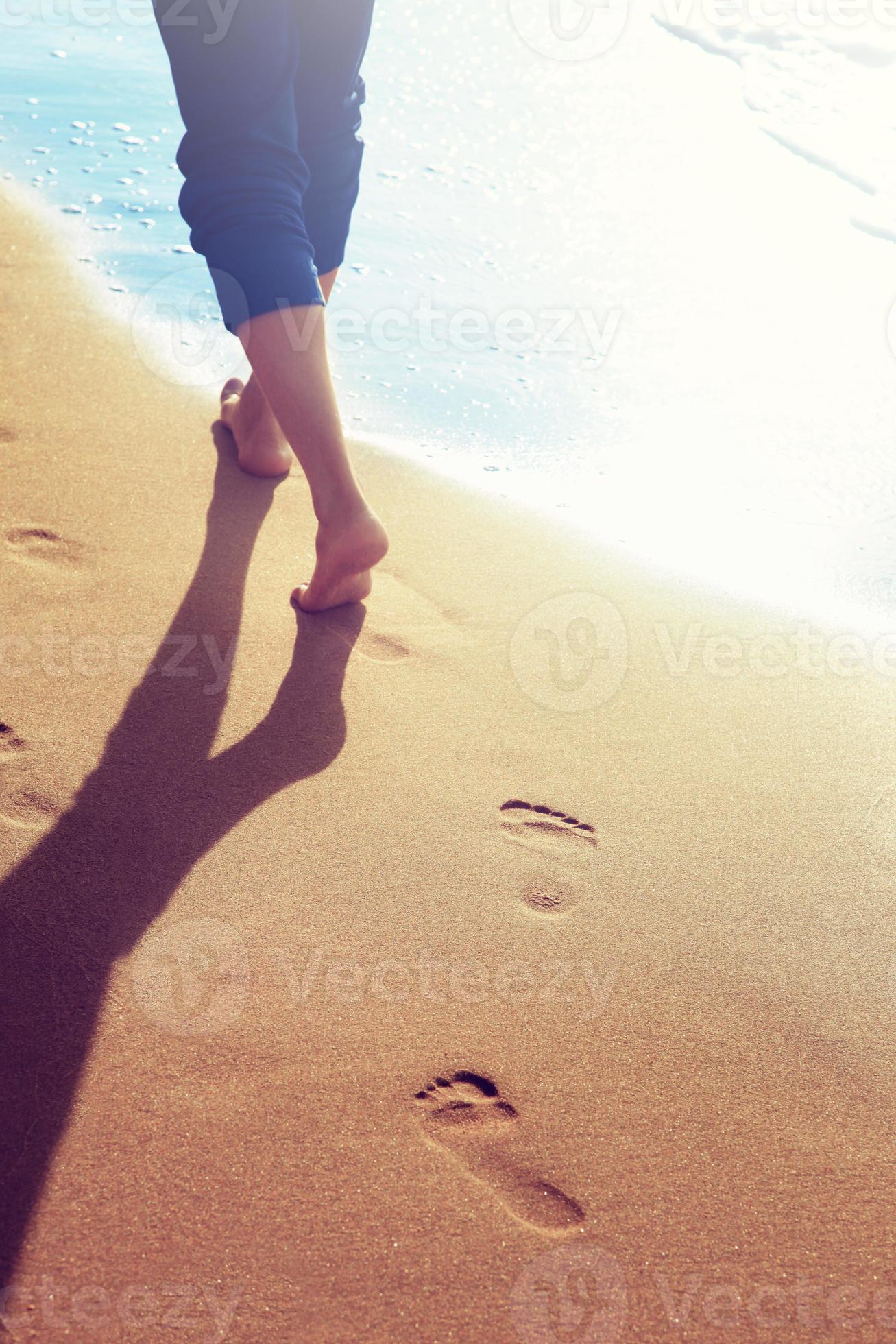 Walking on the beach, leaving footprints in the sand. 8119903 Stock