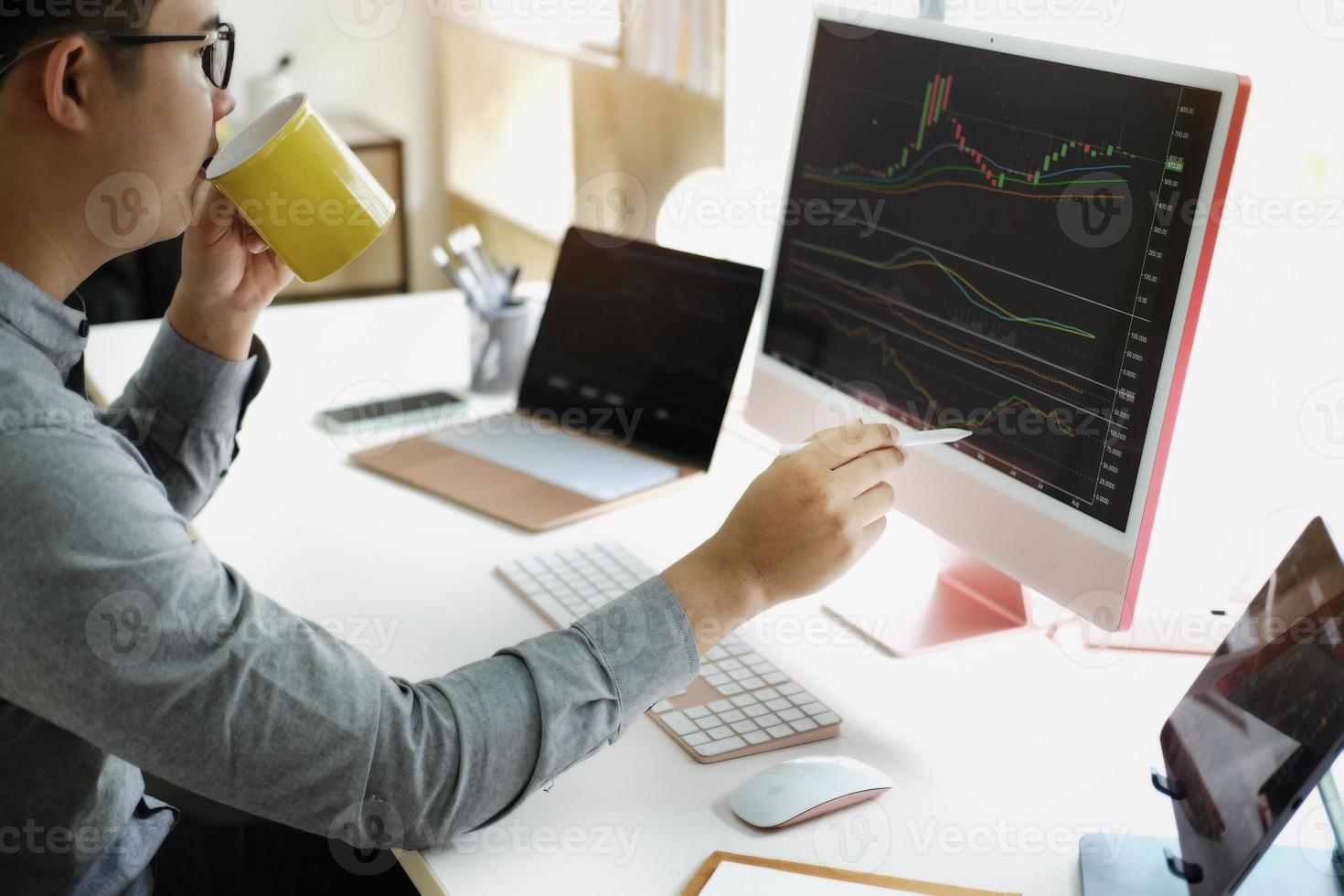 Investment professionals point their pen at their computer monitor to analyze the stock market for profit. photo