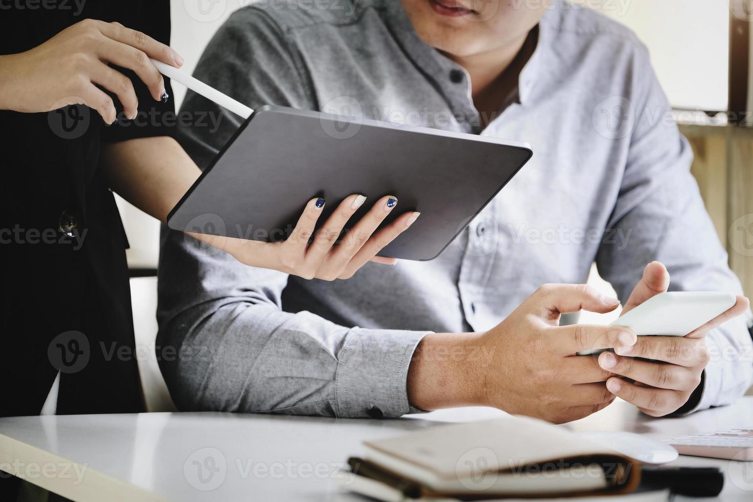 Focus on men using smartphones While the secretary uses a tablet to talk about the company's profitability budget this quarter. photo