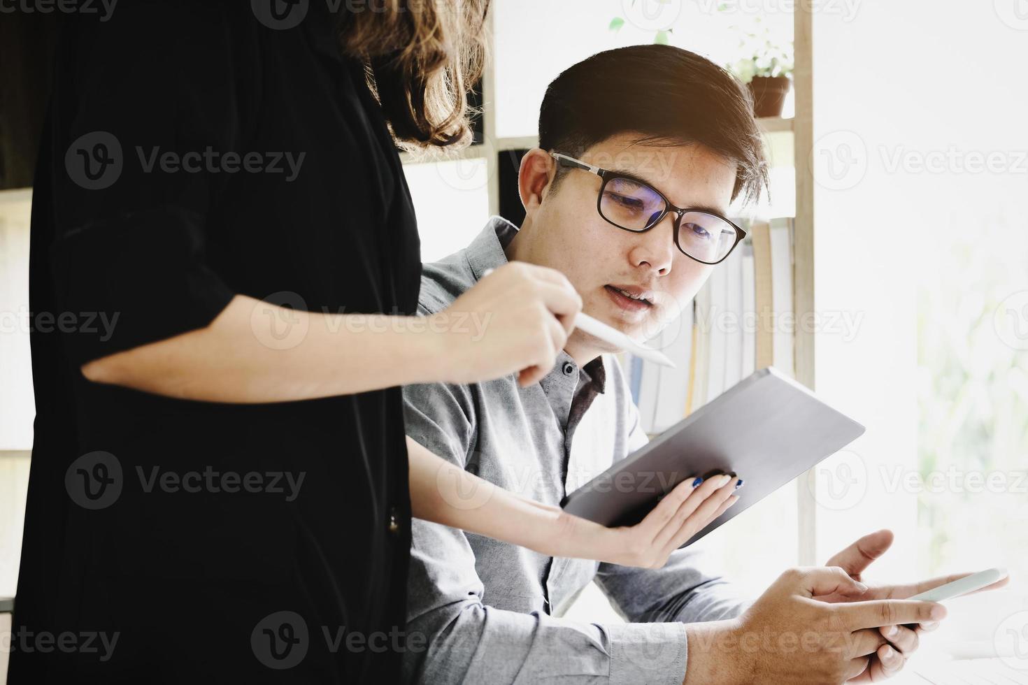 Focus on men using smartphones While the secretary uses a tablet to talk about the company's profitability budget this quarter. photo