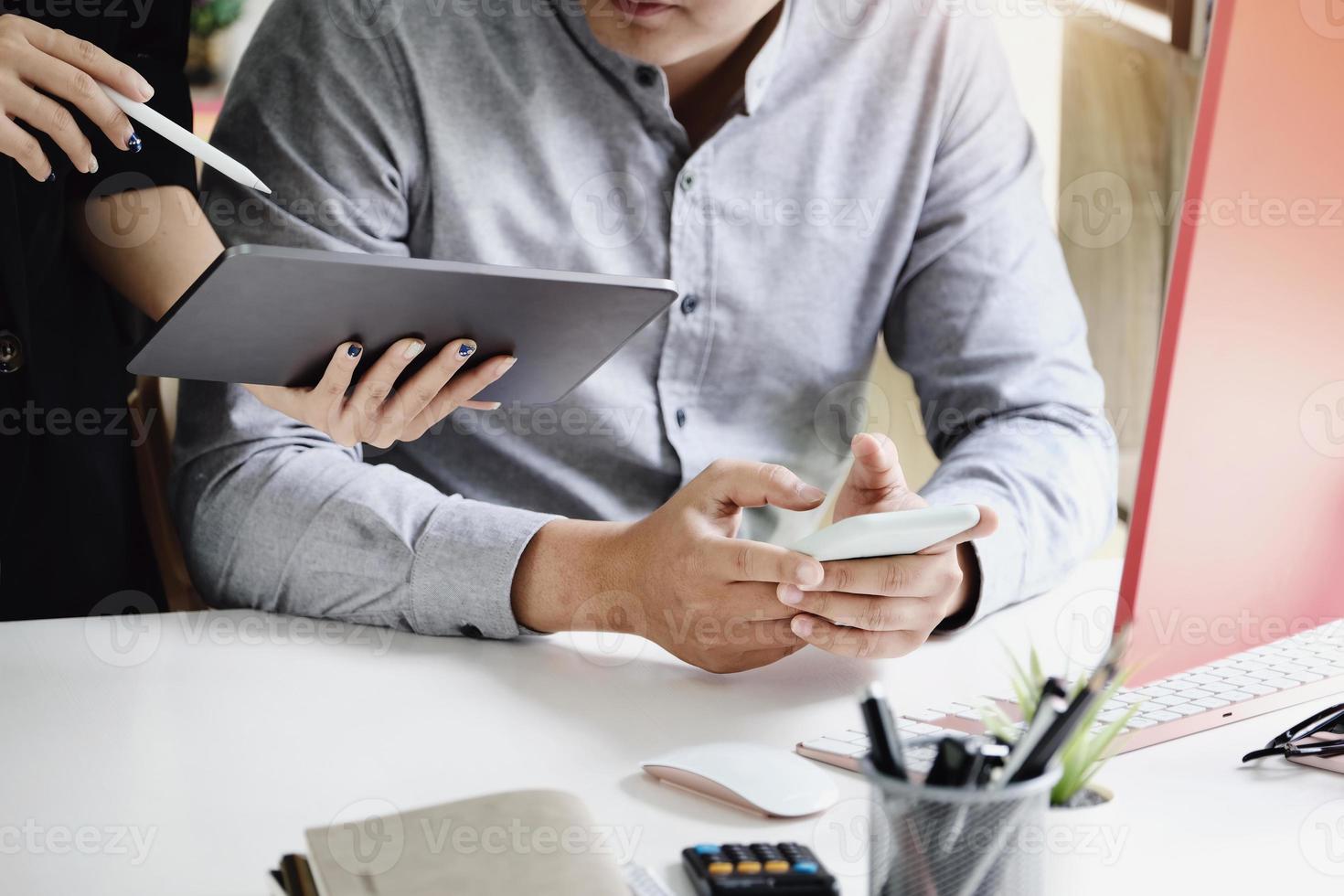 concéntrese en los hombres que usan teléfonos inteligentes mientras la secretaria usa una tableta para hablar sobre el presupuesto de rentabilidad de la empresa este trimestre. foto