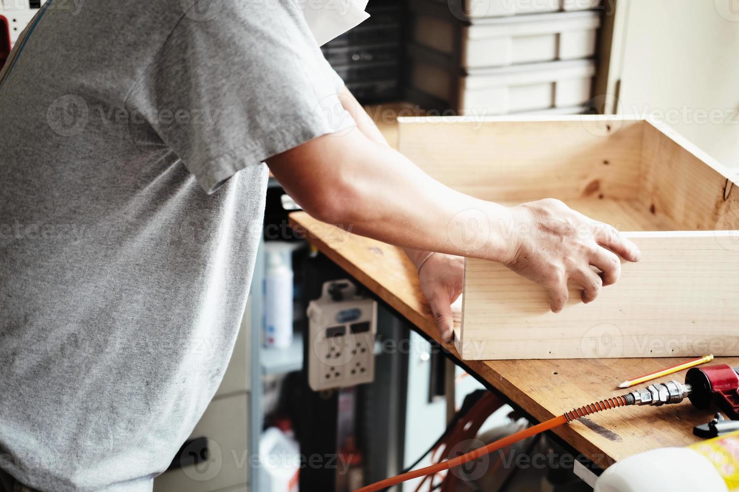 A carpenter measures the planks to assemble the parts, and build a wooden table for the customer. photo