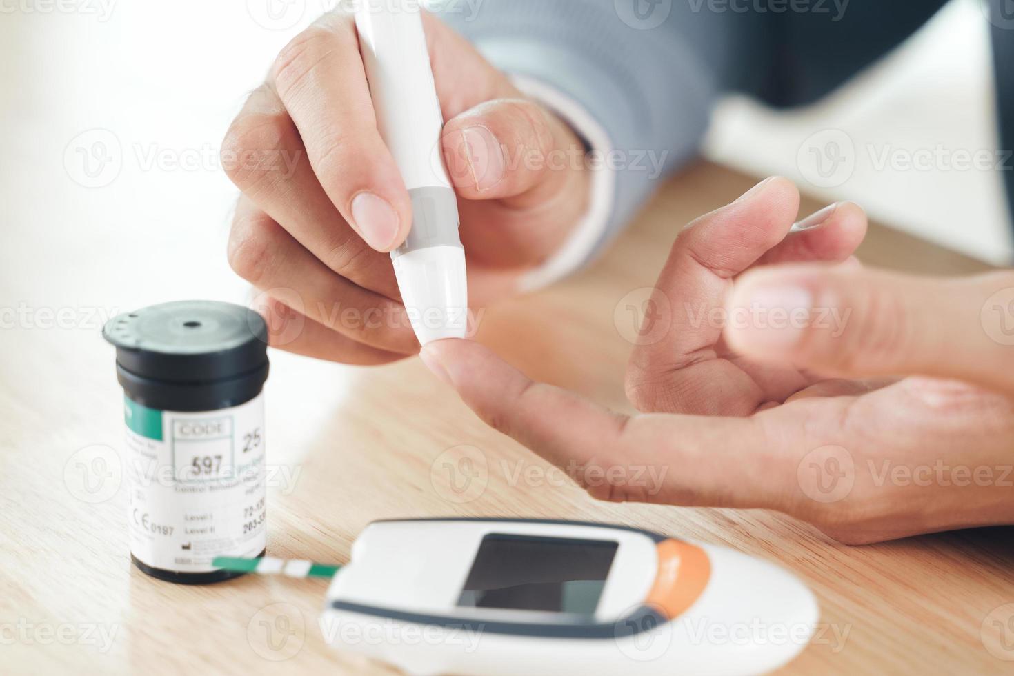 Asian man using lancet on finger for checking blood sugar level by Glucose meter, Healthcare and Medical, diabetes, glycemia concept photo