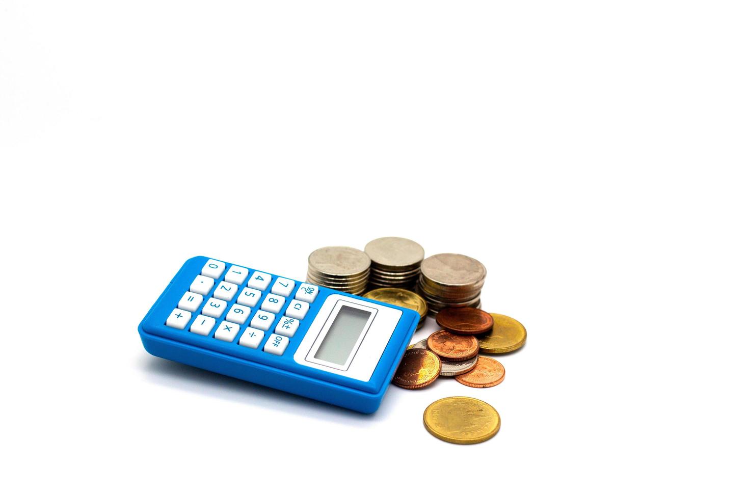 Coins and blue calculator on white background photo