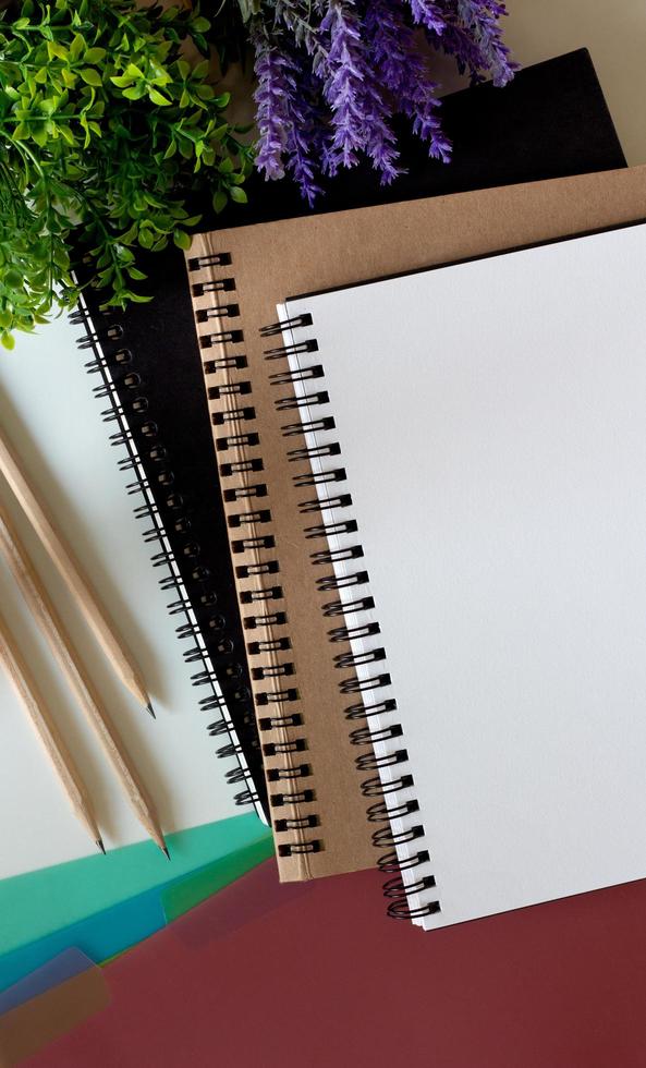 cuaderno de bocetos en blanco, tres lápices de madera e índice de pestañas de colores. foto