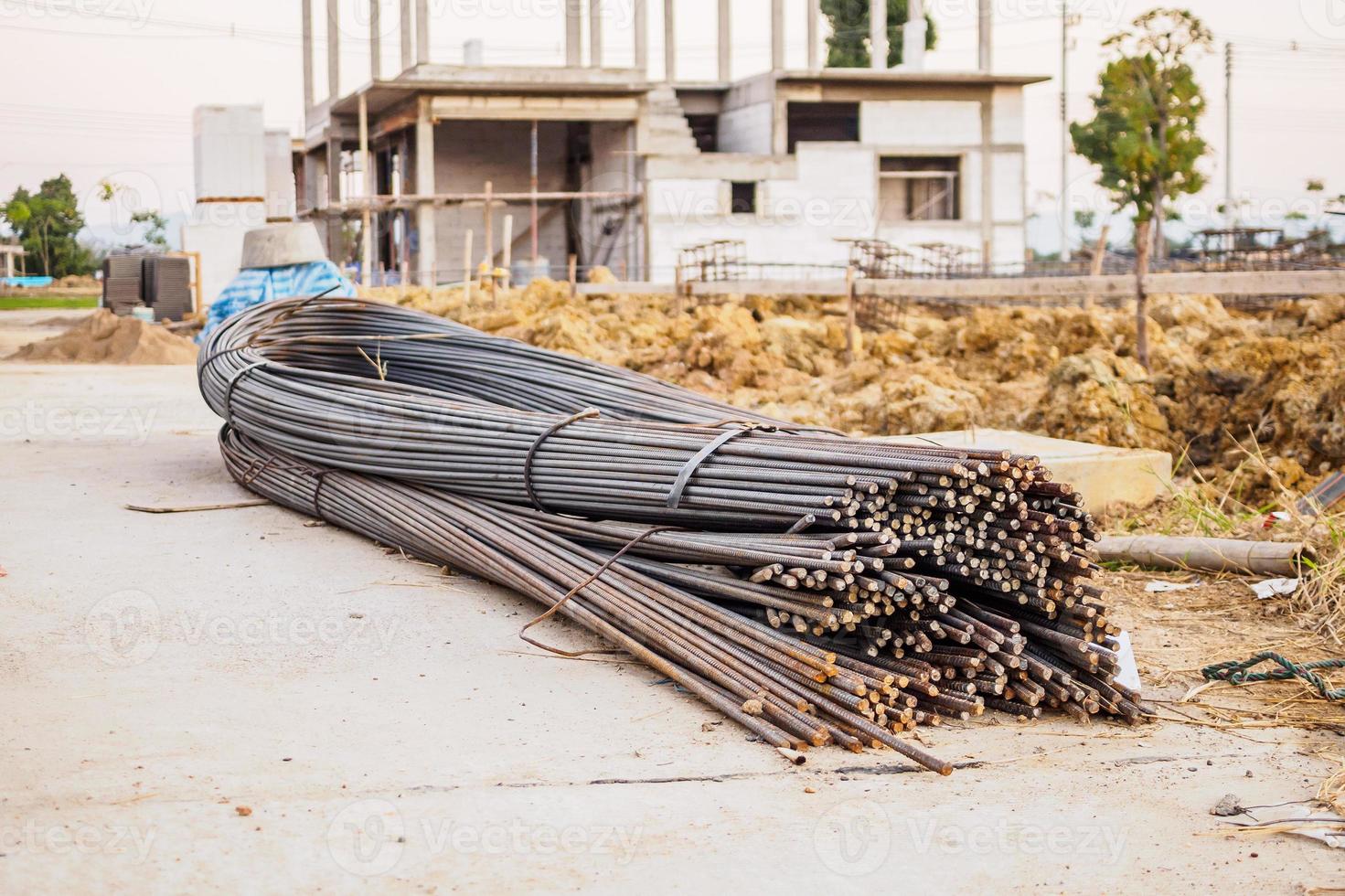 steel rebar for reinforcement concrete at construction site with house under construction background photo