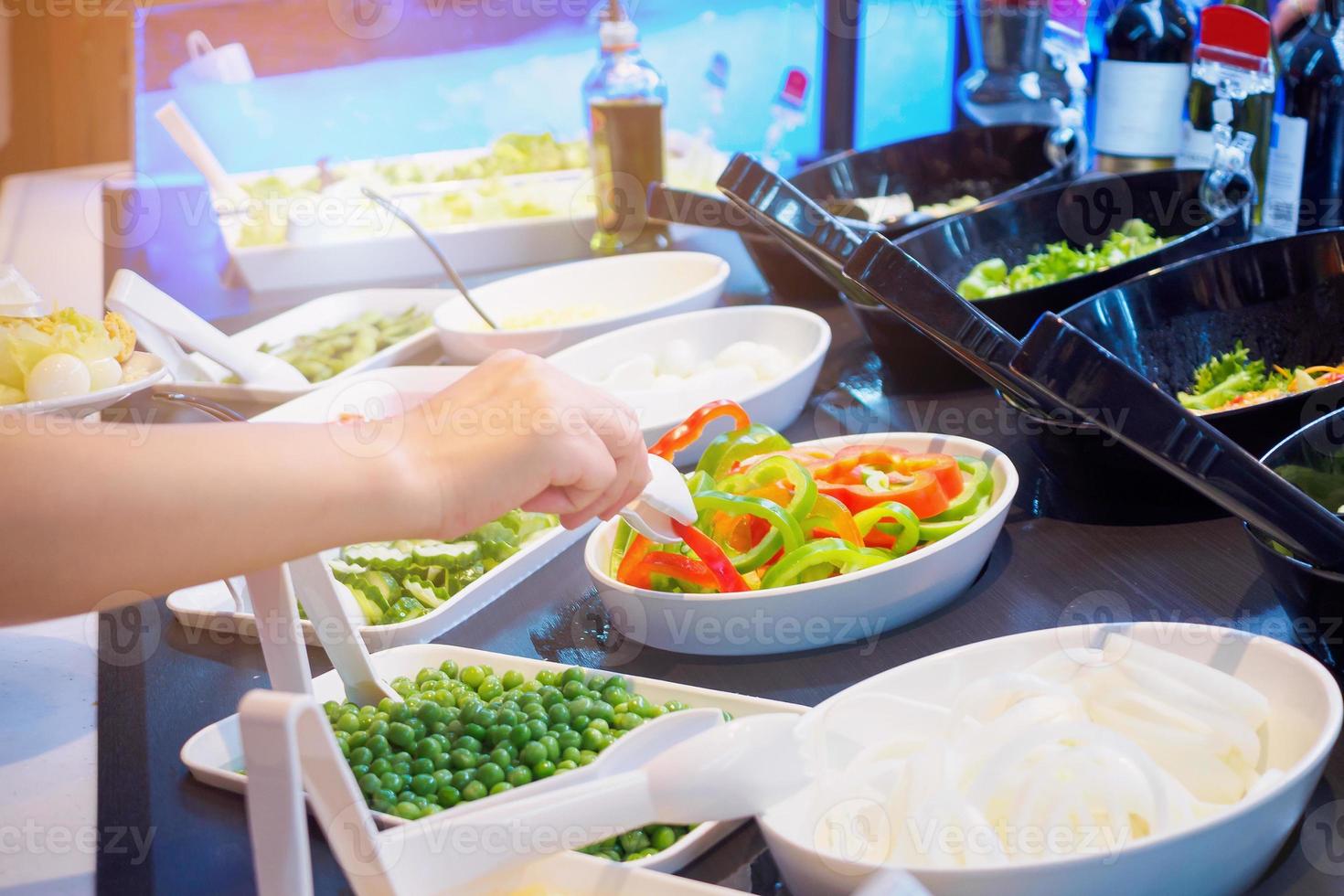 Asian woman choosing vegetable ingredients at salad bar restaurant photo