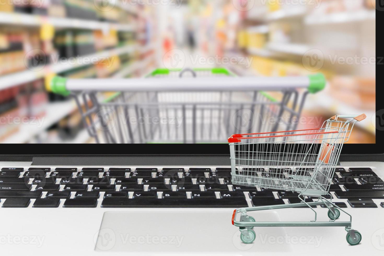 Supermarket cart on laptop computer with blur grocery store on screen Shopping online concept photo