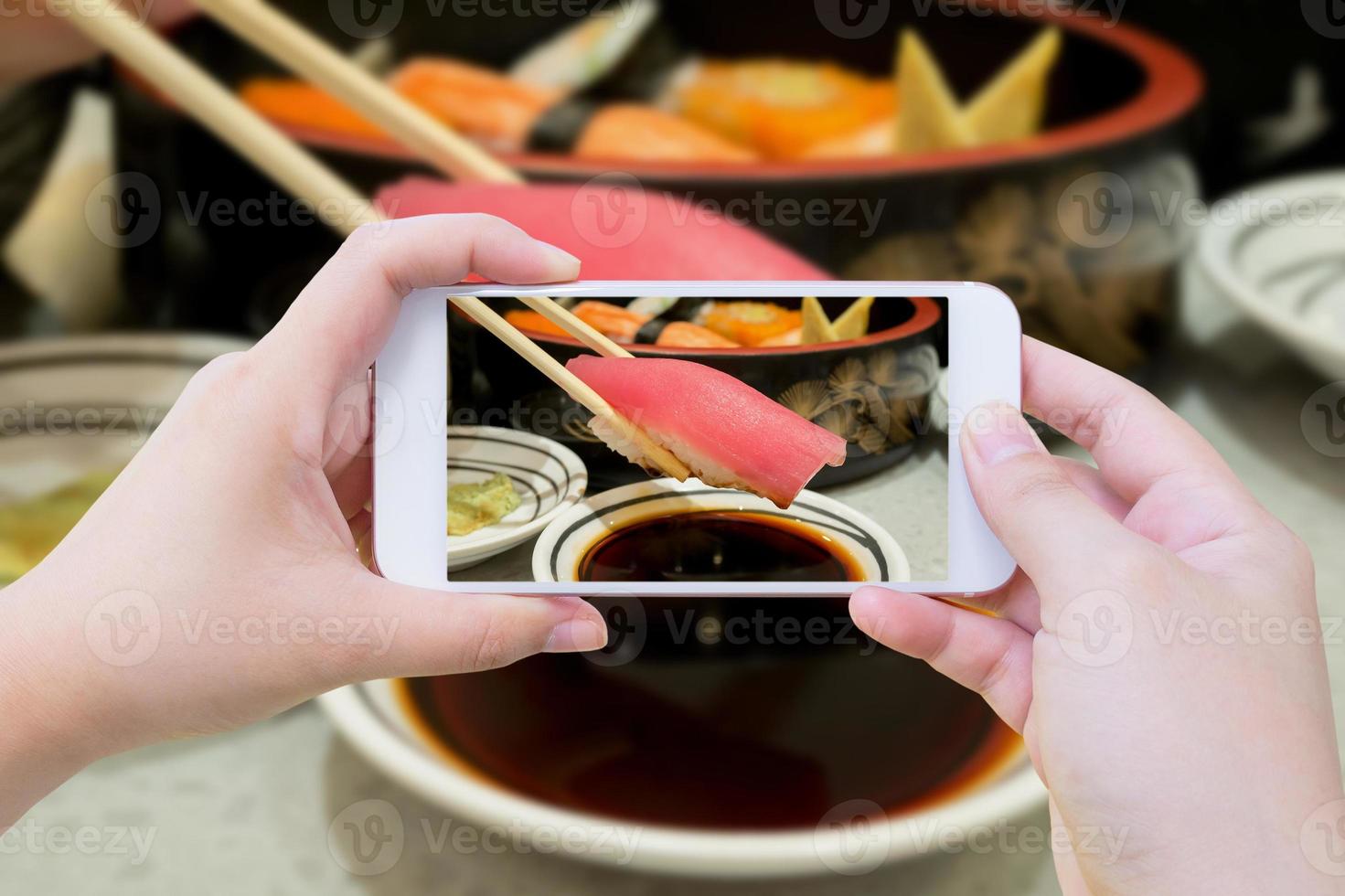 Taking photo of tuna sushi in chopsticks