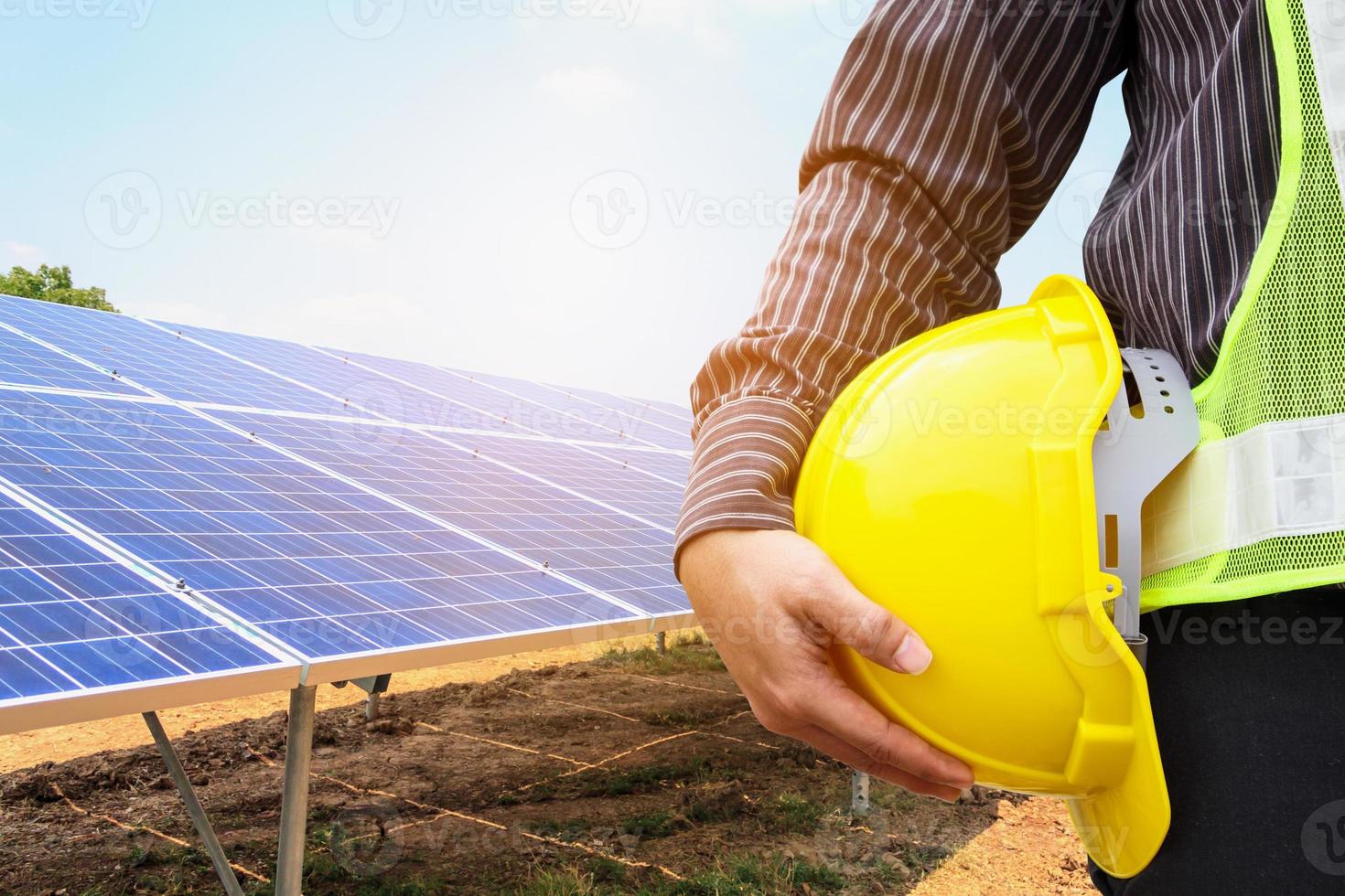 Young business man engineer hold yellow helmet at solar panel power plant construction site background photo