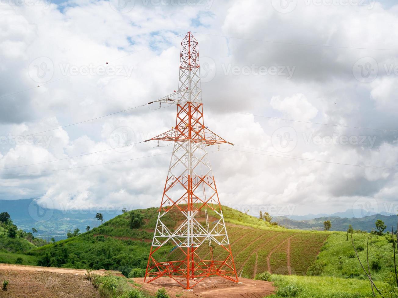 High voltage power lines tower on green mountain photo