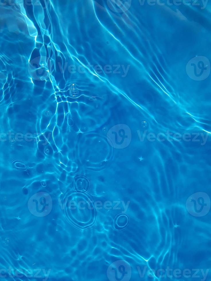 Defocus blurred transparent blue colored clear calm water surface texture with splashes and bubbles. Trendy abstract nature background. Water waves in sunlight. photo