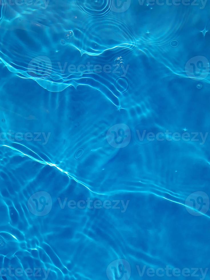 desenfoque borroso transparente color azul claro agua tranquila textura superficial con salpicaduras y burbujas. fondo de naturaleza abstracta de moda. ondas de agua a la luz del sol. foto