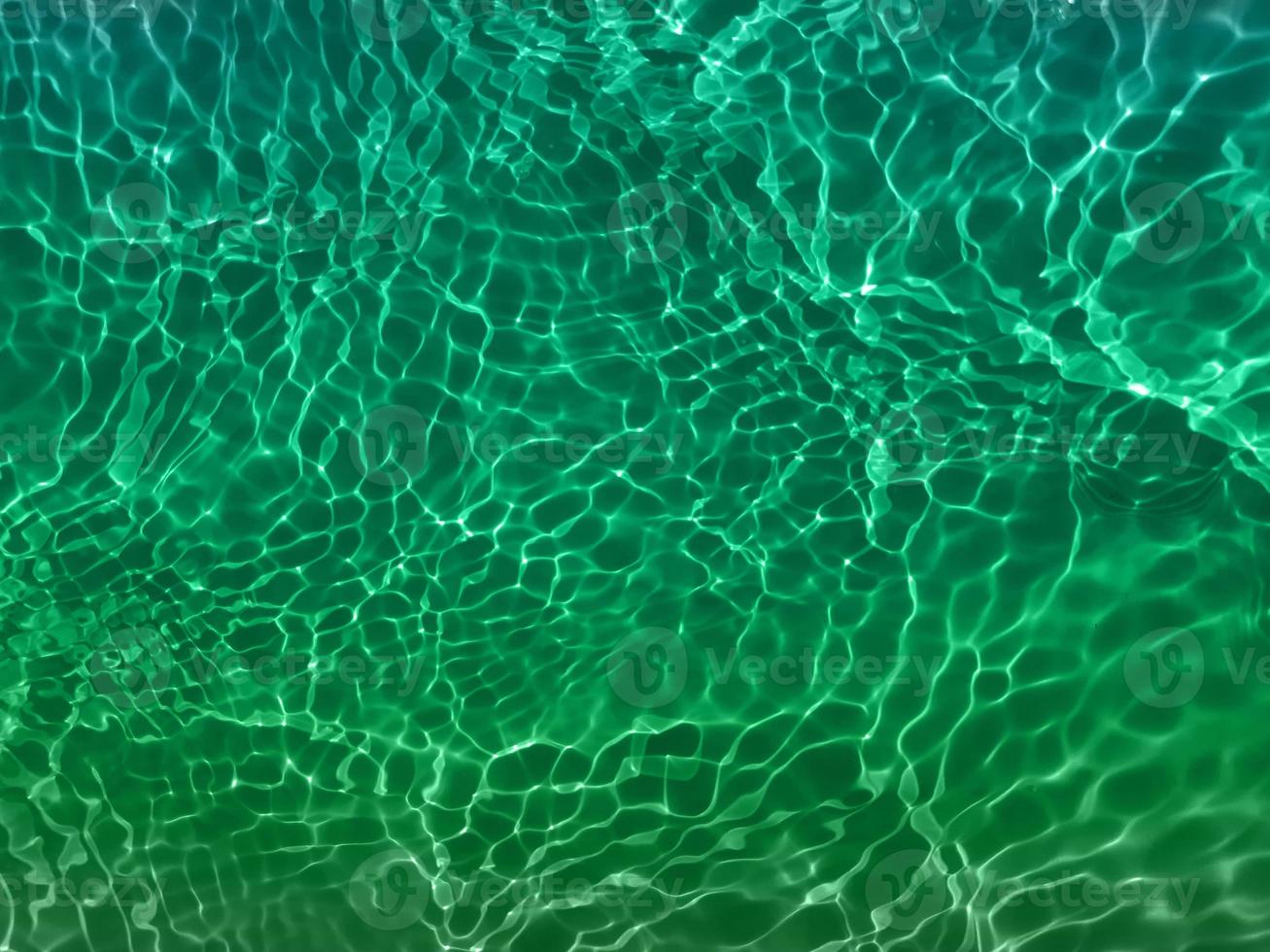 Defocus blurred transparent blue colored clear calm water surface texture with splashes and bubbles. Trendy abstract nature background. Water waves in sunlight. Blue water background. photo
