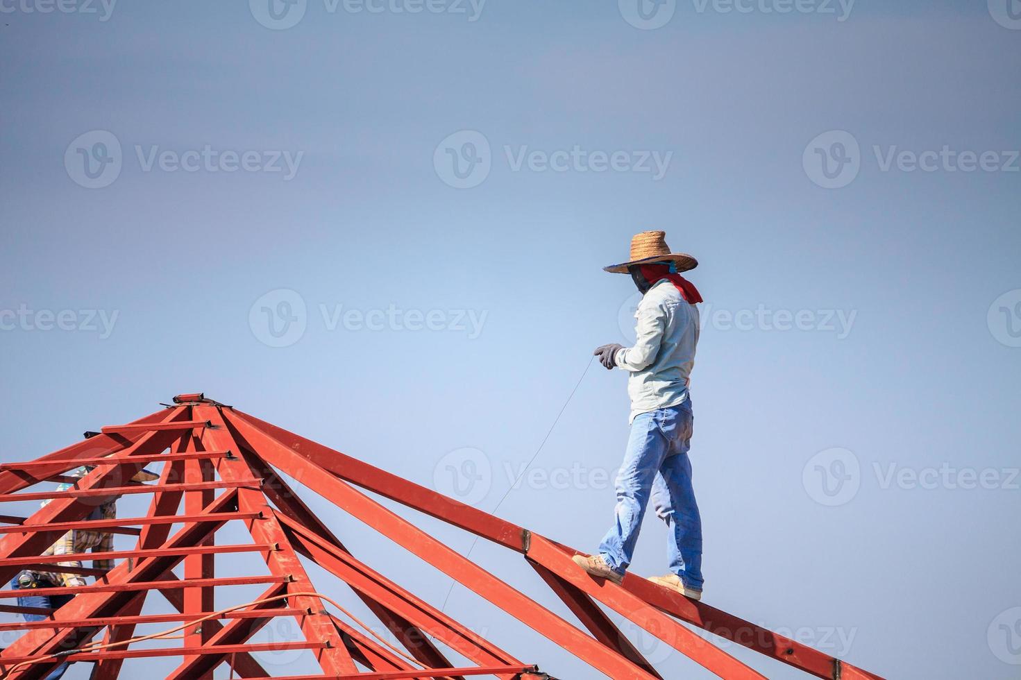 welder workers installing steel frame structure of the house roof at building construction site photo