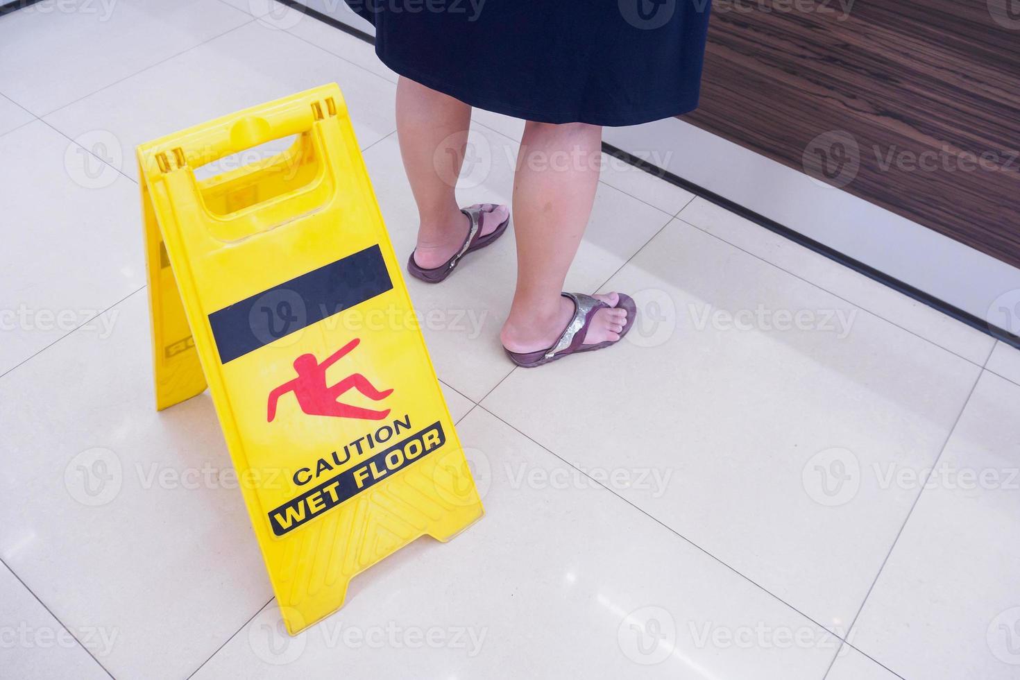 caution wet floor warning sign with people stand nearby photo