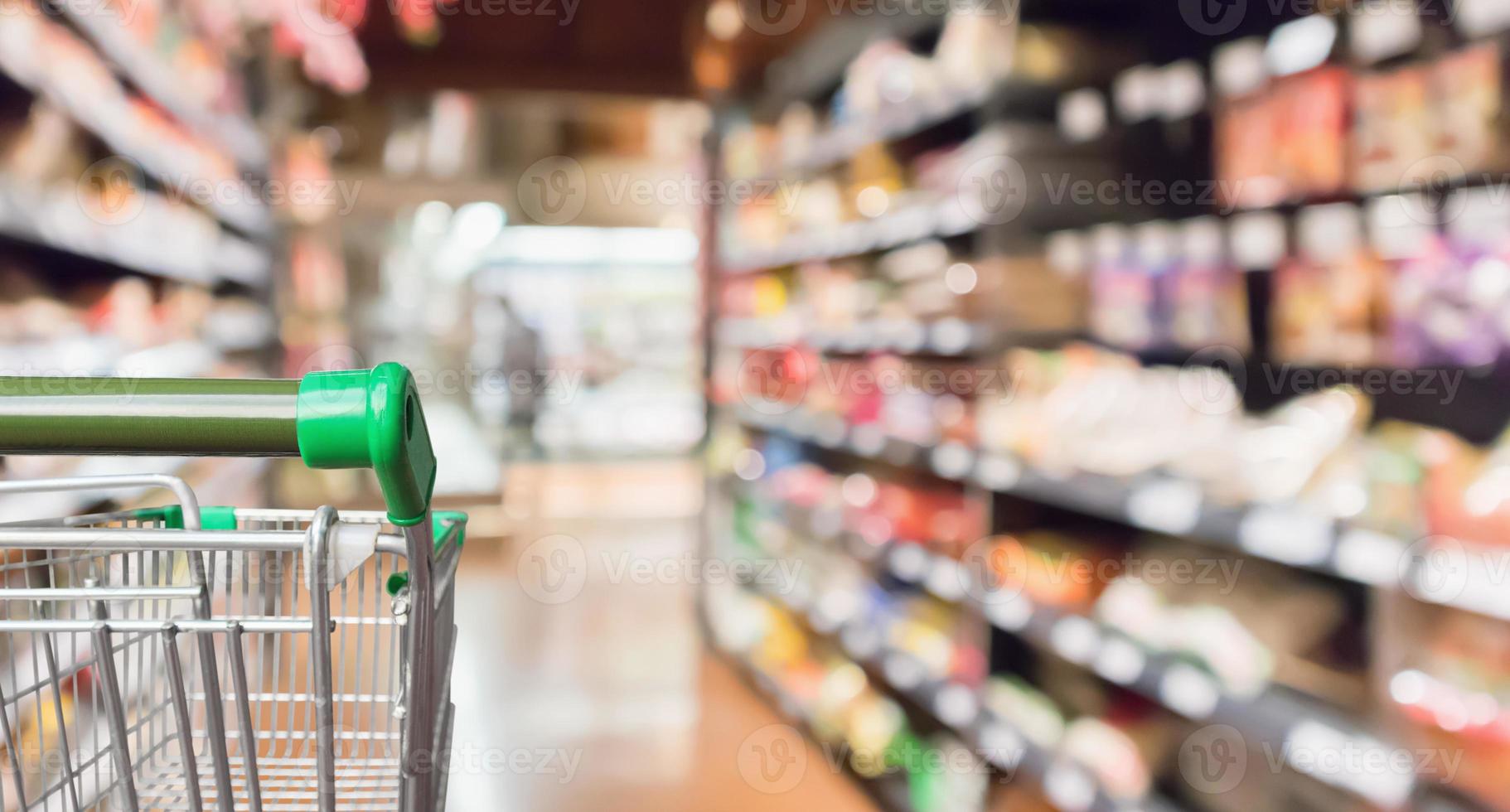 carrito de compras de supermercado verde vacío con pasillo de tienda de comestibles borroso abstracto fondo desenfocado foto