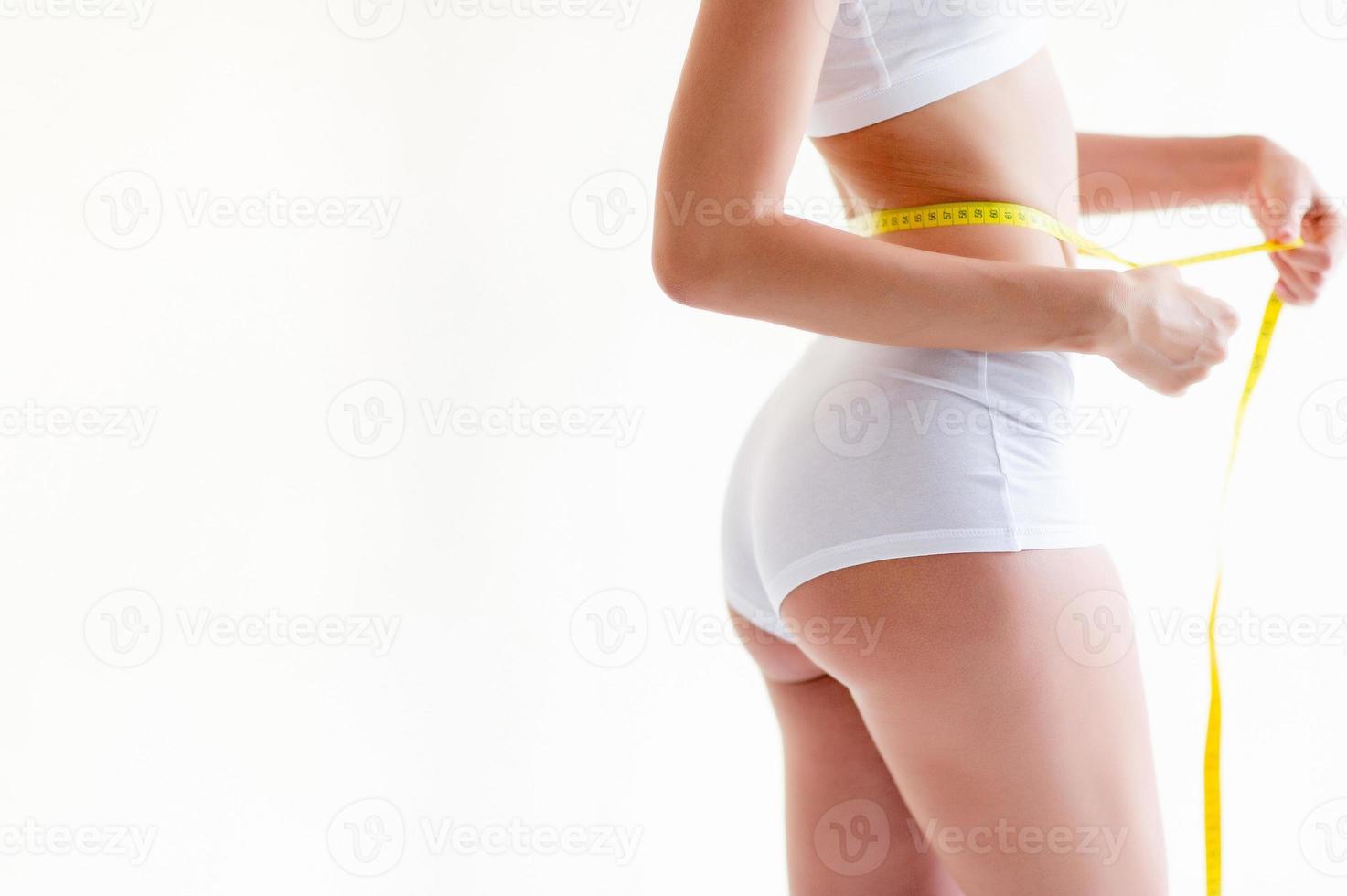 Measure around the waist, beautiful figure Close-up of a slender woman measuring around the waist and torso. Healthy nutrition and weight loss concepts. photo