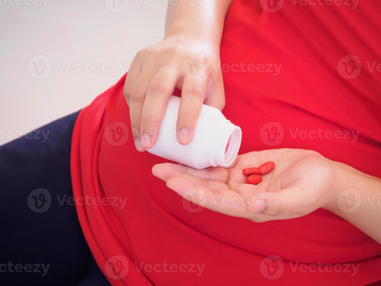 pregnant woman with vitamin pills on her hand photo