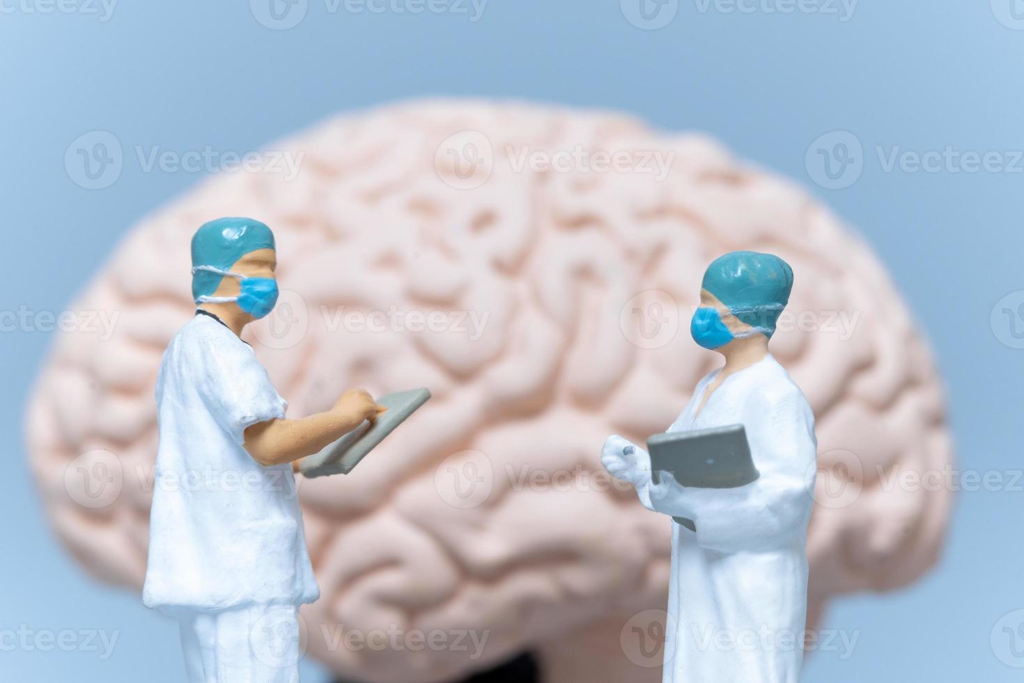 cirujano de personas en miniatura analizando el cerebro del paciente foto