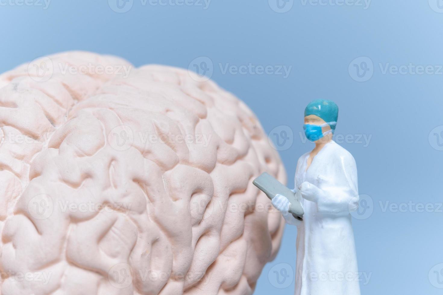 cirujano de personas en miniatura analizando el cerebro del paciente foto