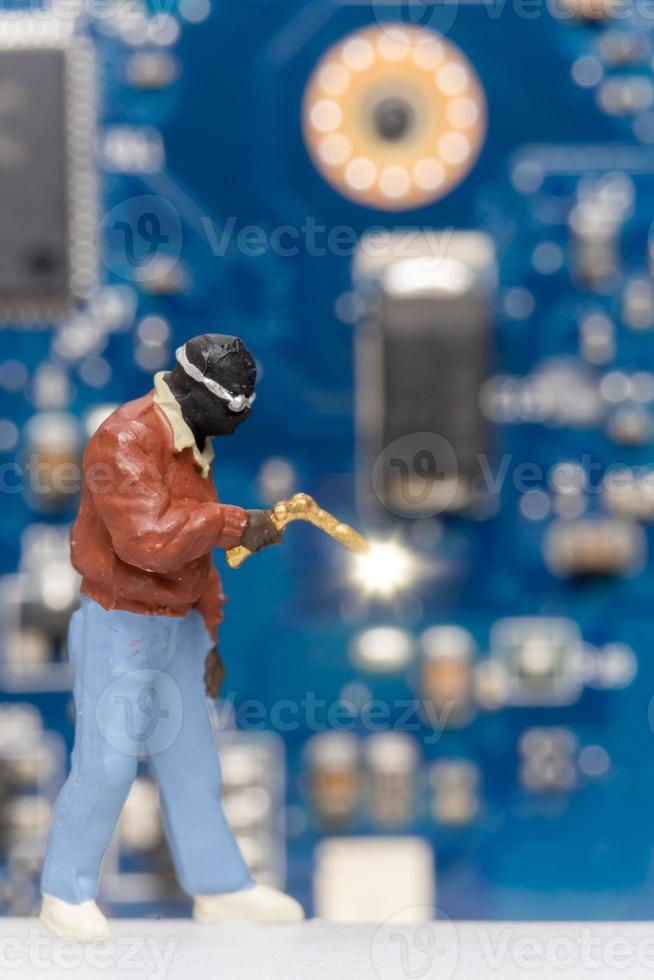 Miniature people Computer repair technicians repair an electronic board with gas photo