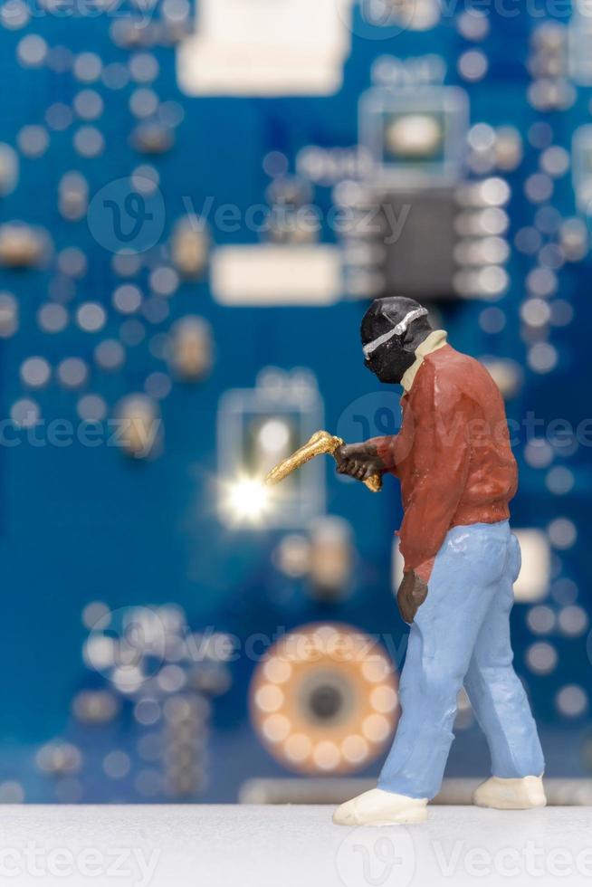 Miniature people Computer repair technicians repair an electronic board with gas photo