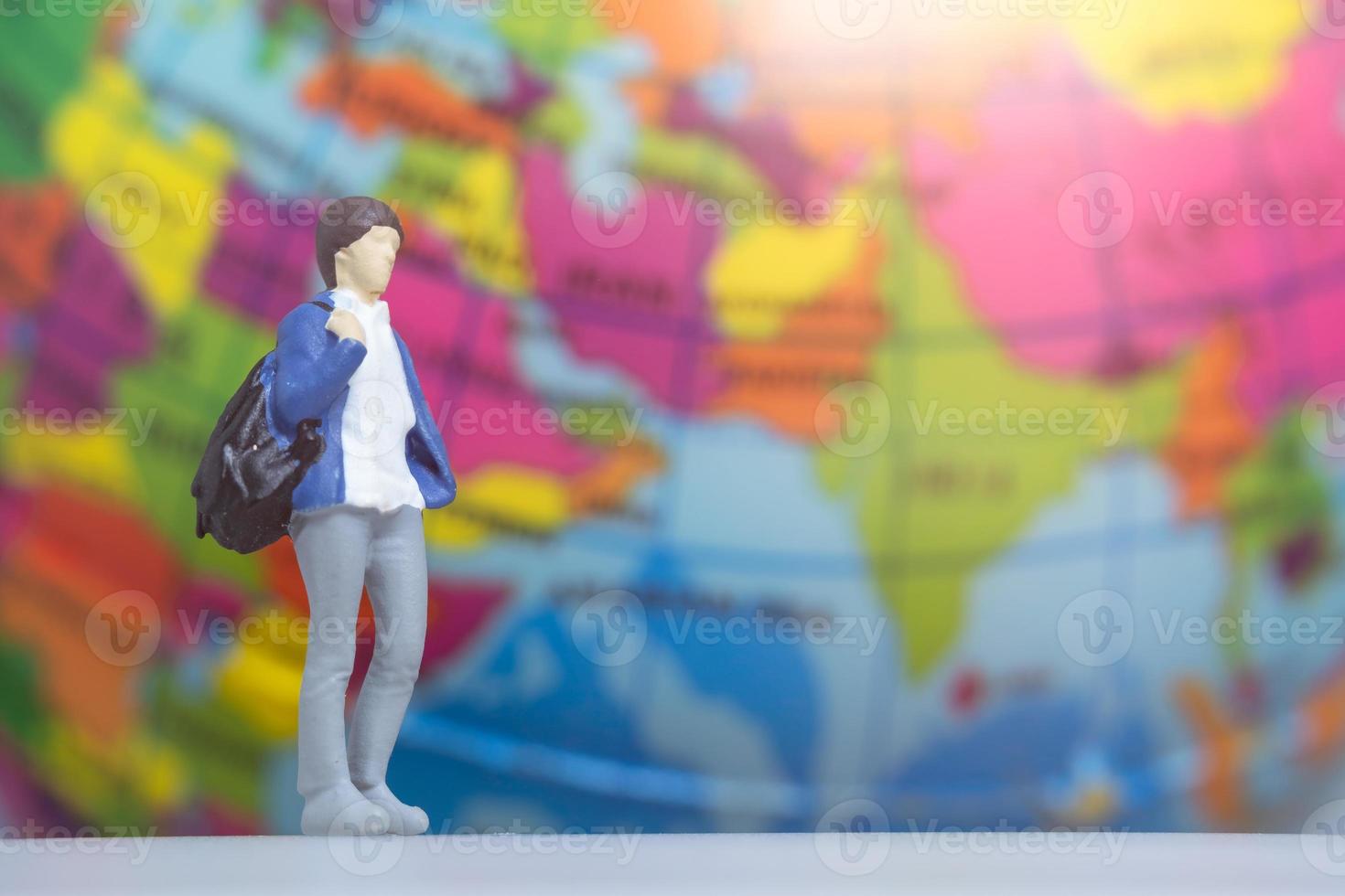 Miniature People Traveler with backpack on The Globe background photo