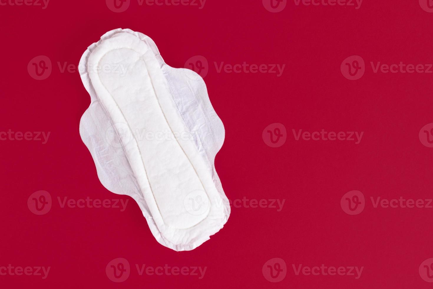 One Feminine Sanitary Pad, Napkin. Means of feminine hygiene during the menstrual cycle. Red background. Copy space. photo