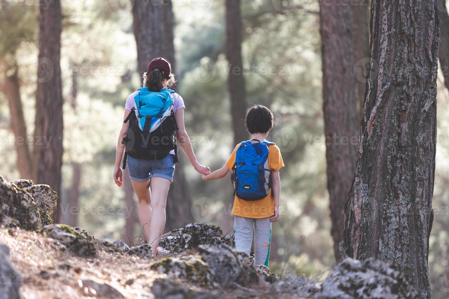 un niño con una mochila viaja con su madre foto