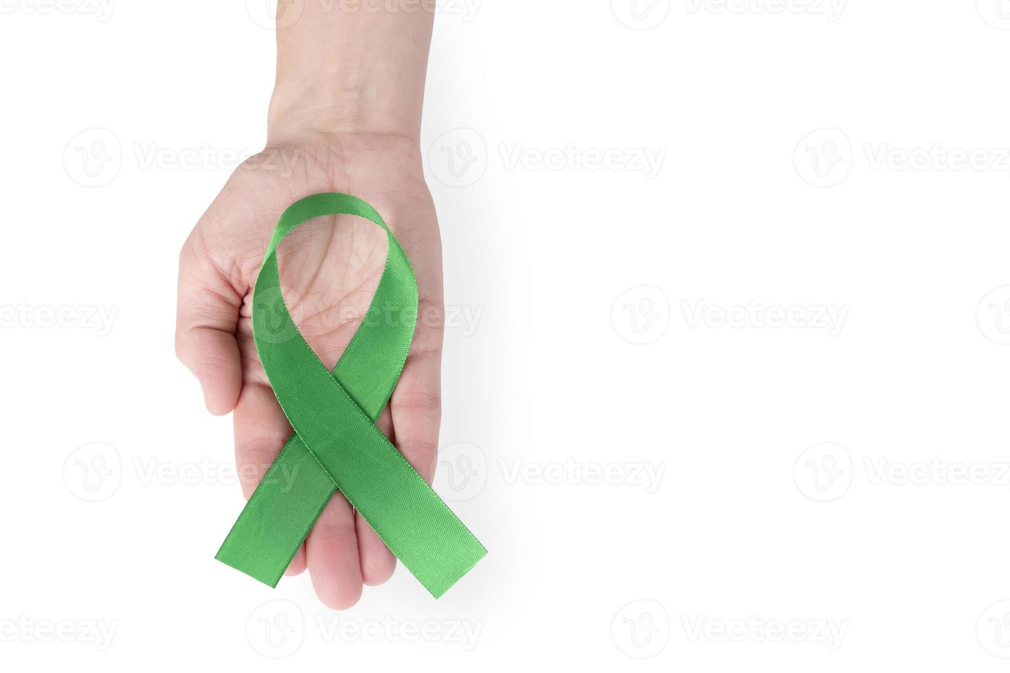 Green satin ribbon on the palm of a woman, isolated on a white background. Cancer awareness symbol. copy space. photo