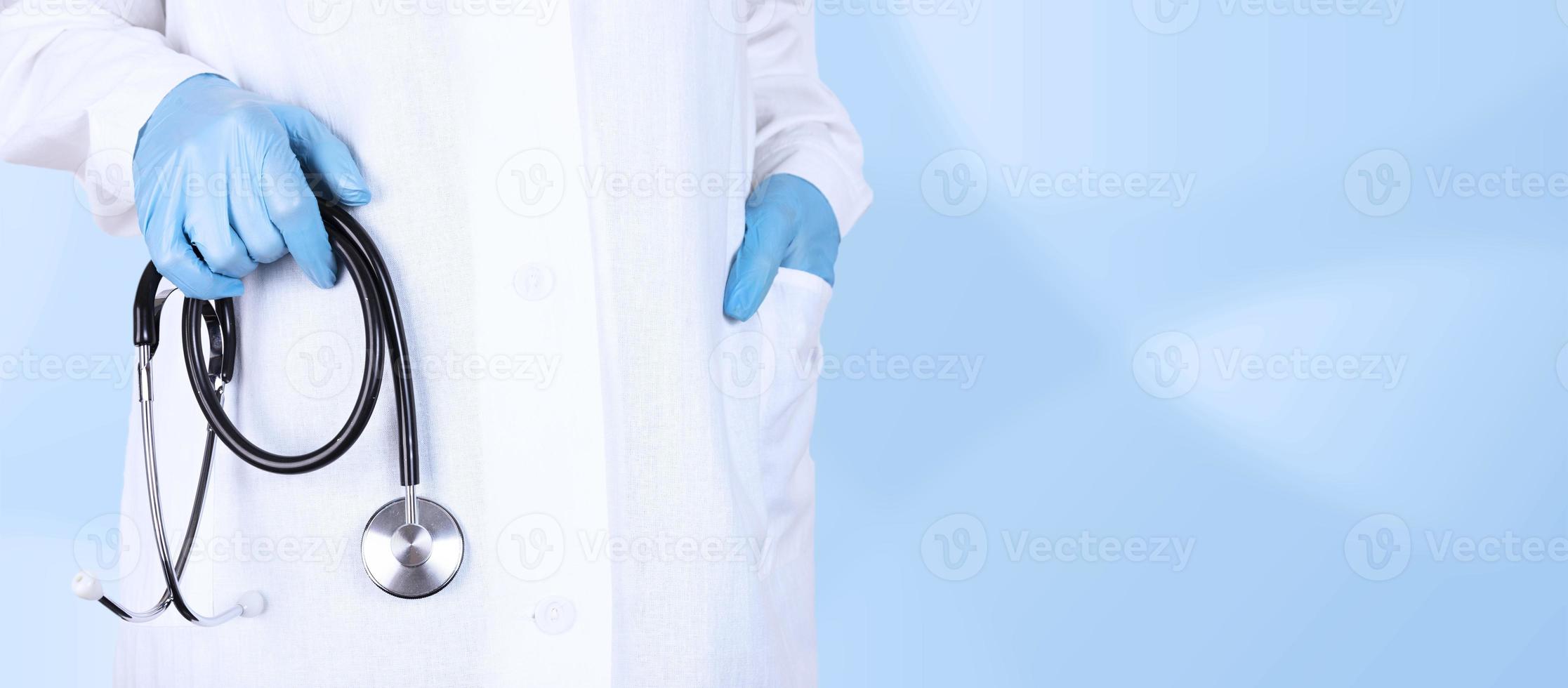 Professional elderly male doctor or cardiologist in white uniform holding a stethoscope in his hand. Cardiology medical clinic, heart treatment concept. Close up view, copy space. photo