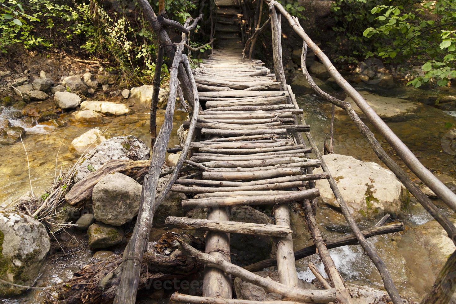 Wooden flooring of a dilapidated bridge over a mountain river on an ecological trail in a summer mountain forest. photo