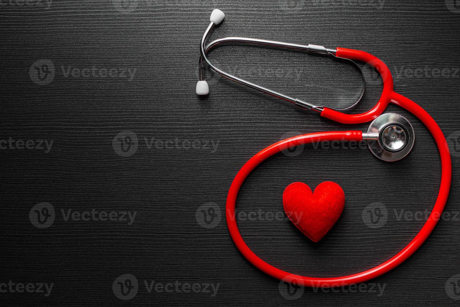 Stethoscope doctor with red heart on black wooden table background with space for text. photo