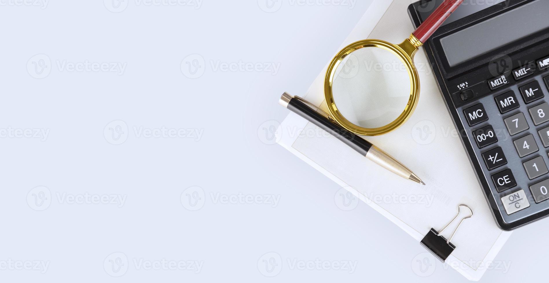 Calculator, pen, magnifying glass and a stack of documents on the auditor's desktop preparing the annual, financial report and balance sheet. The concept of accounting and auditing. copy space. photo