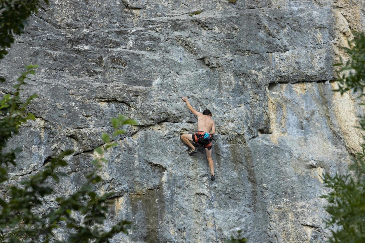 An extreme man, a rock climber on a sheer gray-red rock in the Crimean mountains. photo