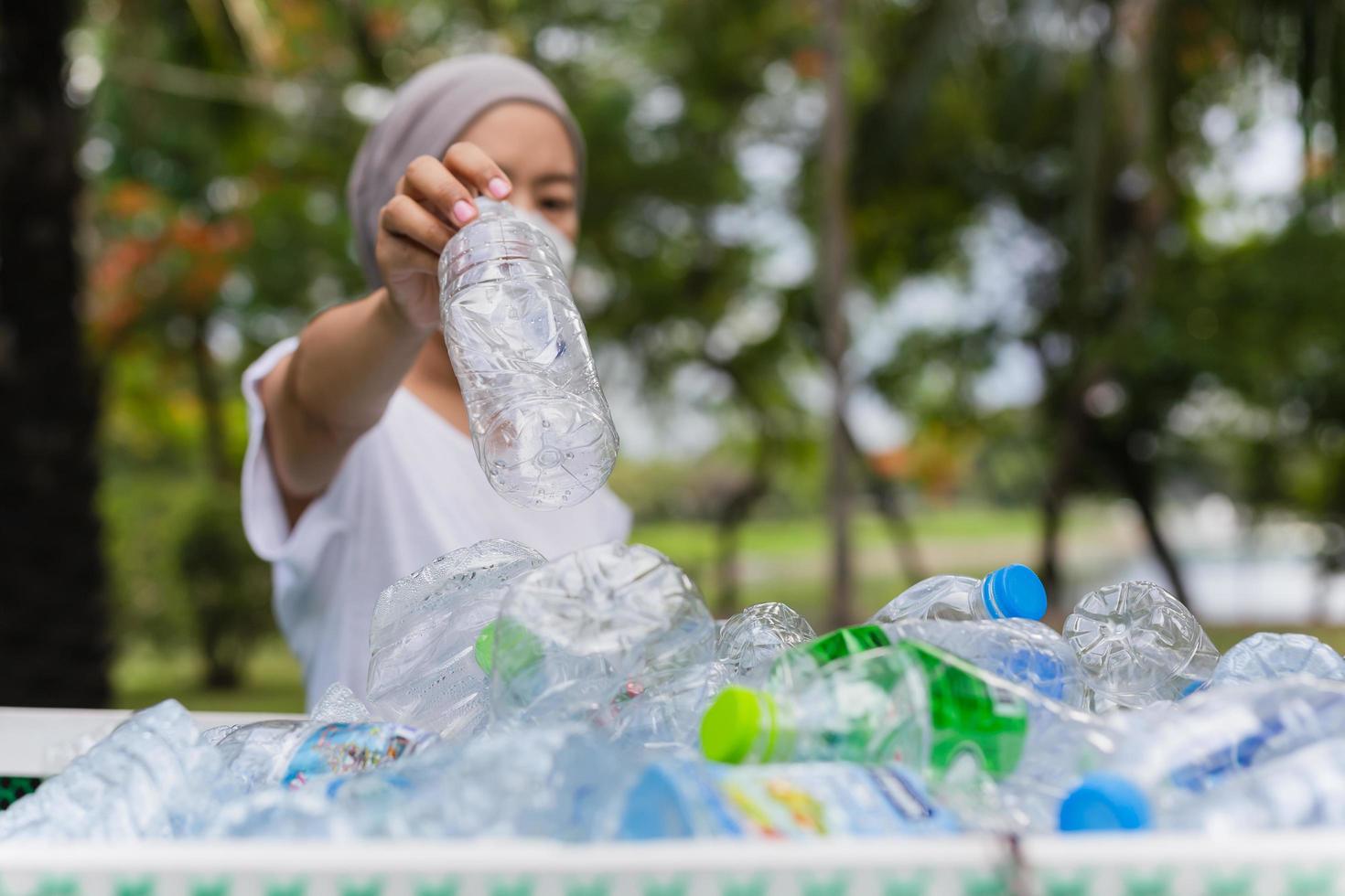 Woman hand holding recycle plastic bottle in garbage bin environment conceptual. photo