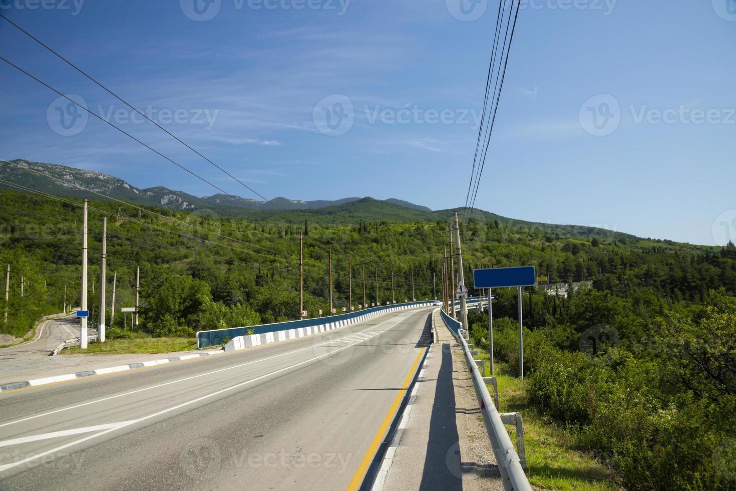 Automobile bridge with an asphalt road passing through a mountain European river. photo