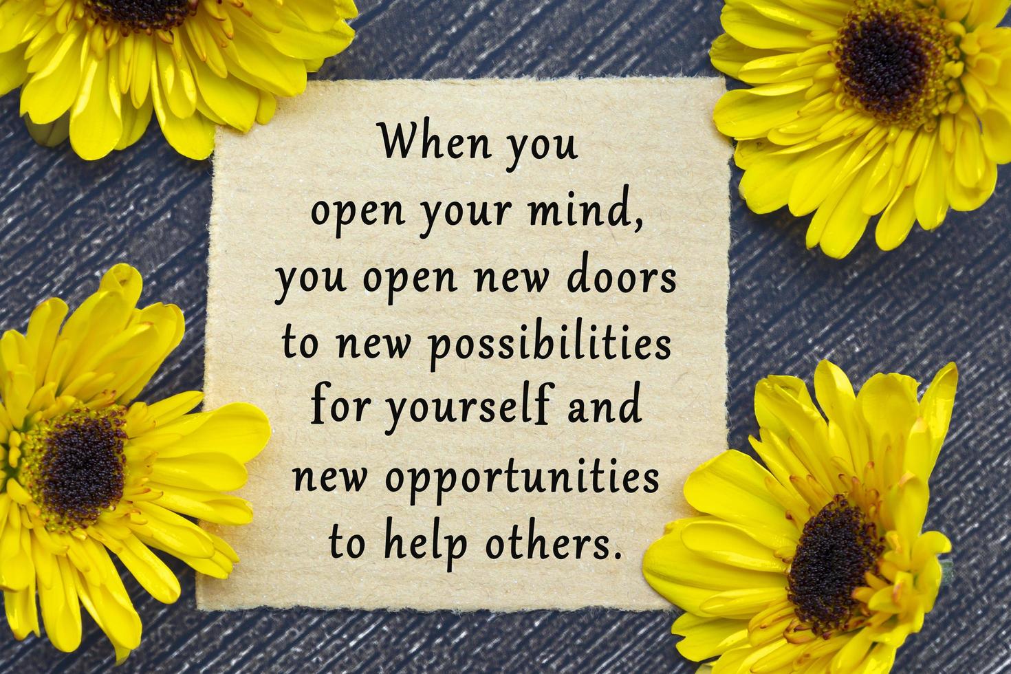 Motivational quote on torn brown paper on wooden surface with sunflowers. photo