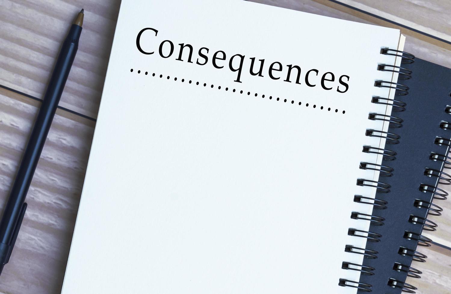 Consequences word written on notepad on wooden desk. photo