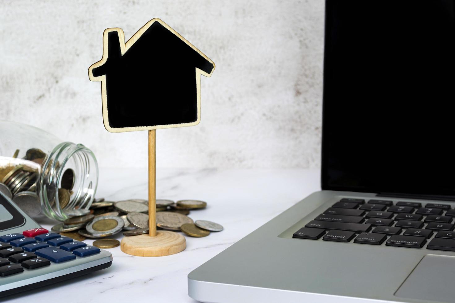 Wooden house model with blurred background of coins, calculator and notebook. photo