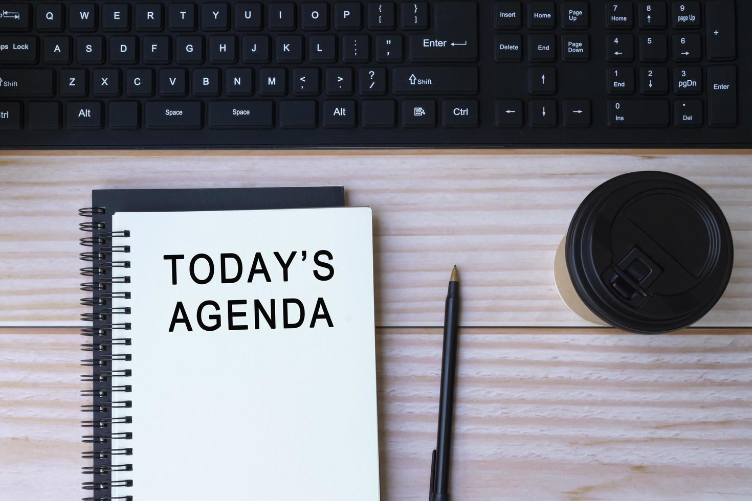 texto de la agenda de hoy en un bloc de notas con teclado, bolígrafo y taza de café desechable. foto