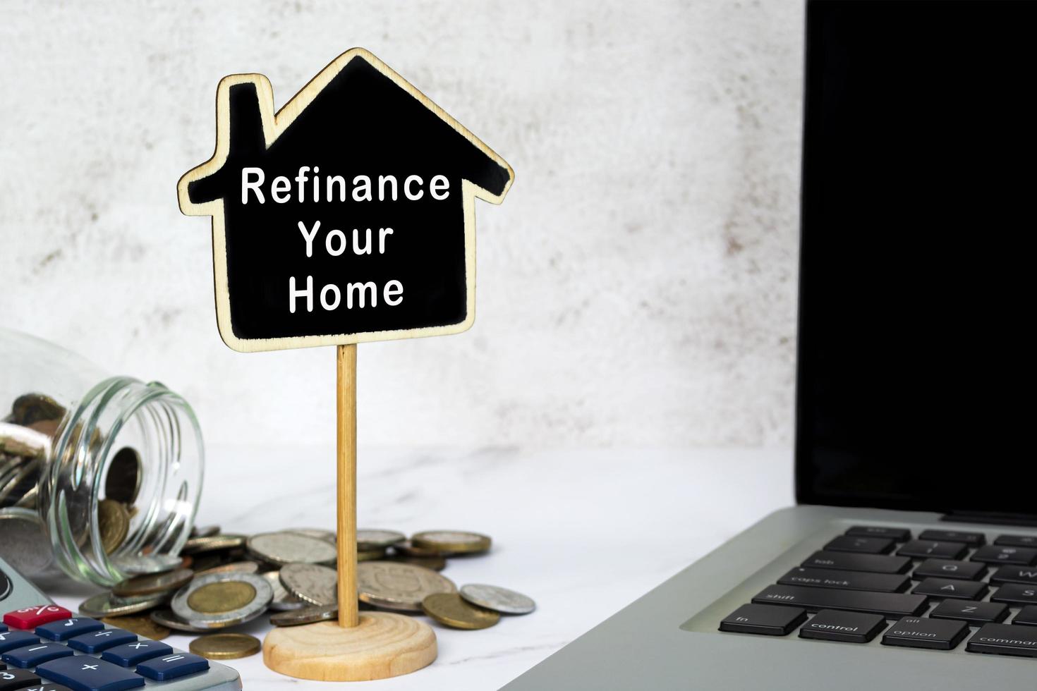 Refinance Your Home text on wooden house model with blurred on white desk. photo