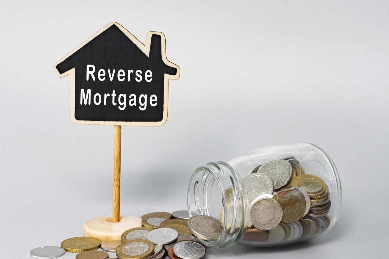 Reverse Mortgage text on wooden house model with coins in a glass jar. photo