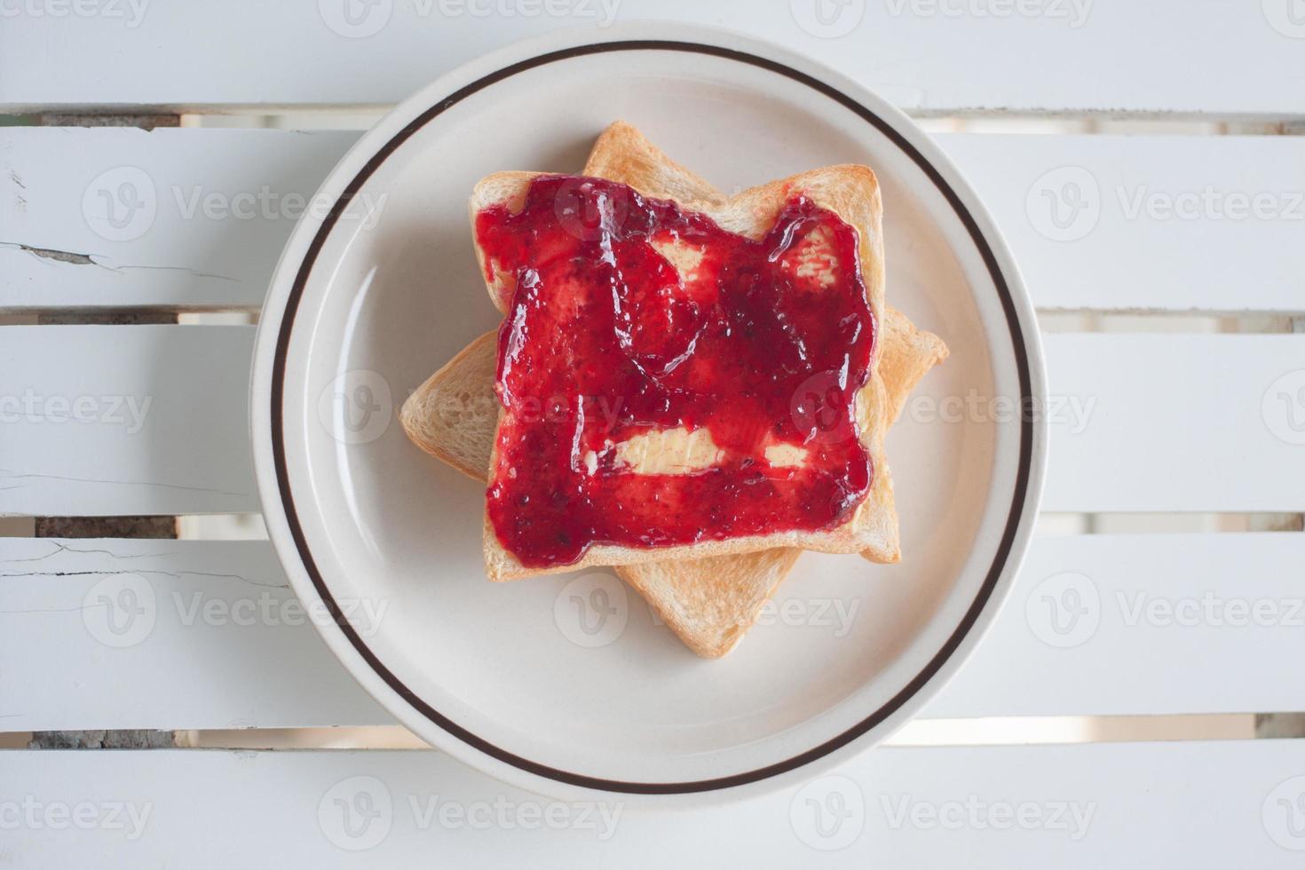 closeup top view of slice of toast bread with jam on wood table photo